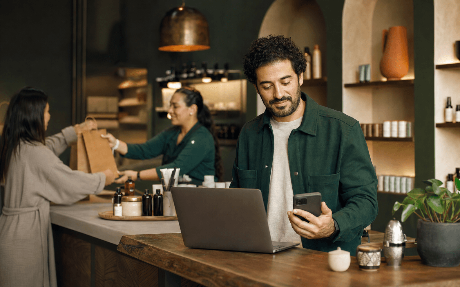 A business owner checking customer requests while the team serves a customer